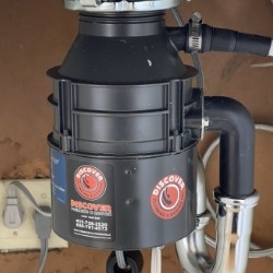 An installed garbage disposal unit with the DiscoverPlumbing&Rooter logo, showcasing efficient plumbing solutions in San Francisco.